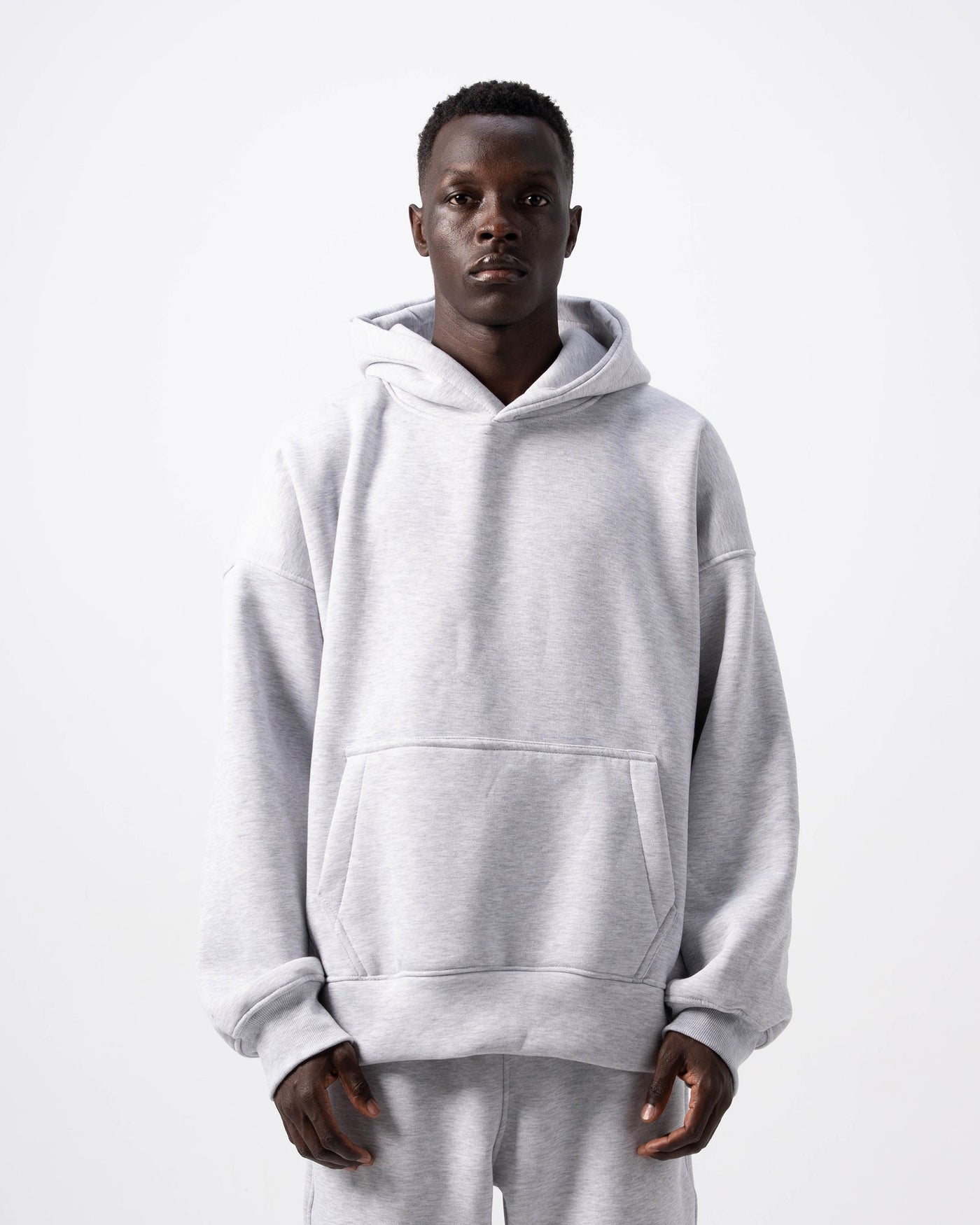 Person wearing a gray hoodie and pants set on a white background